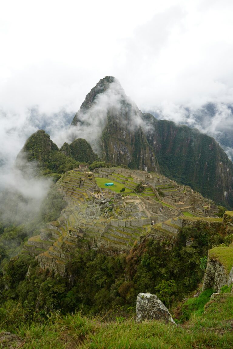 The Machu Picchu ruins partially obscured by drifting clouds and morning mist