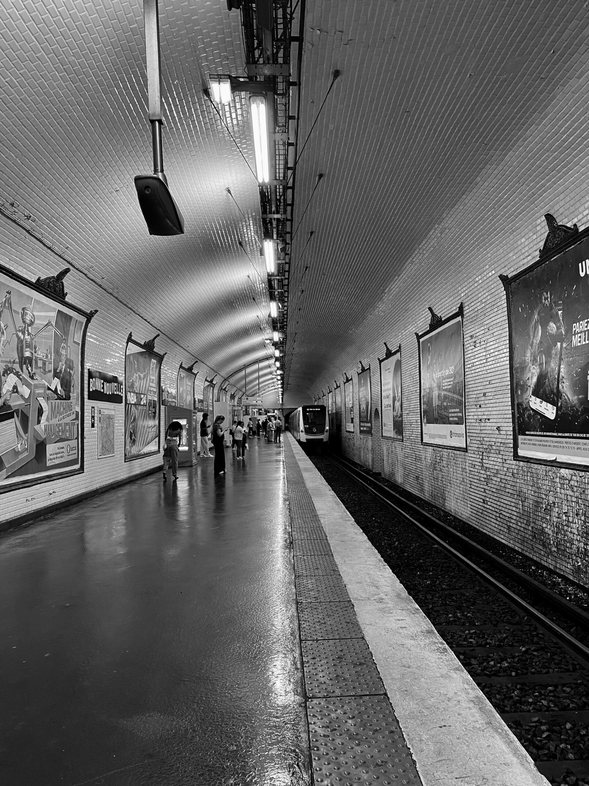 A black and white photograph of a Paris Metro subway station platform