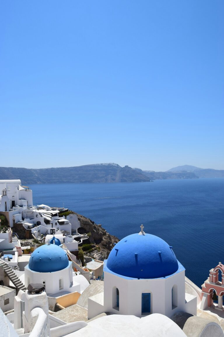 Whitewashed buildings with iconic blue domes overlooking the sea in Oia, Santorini, Greece