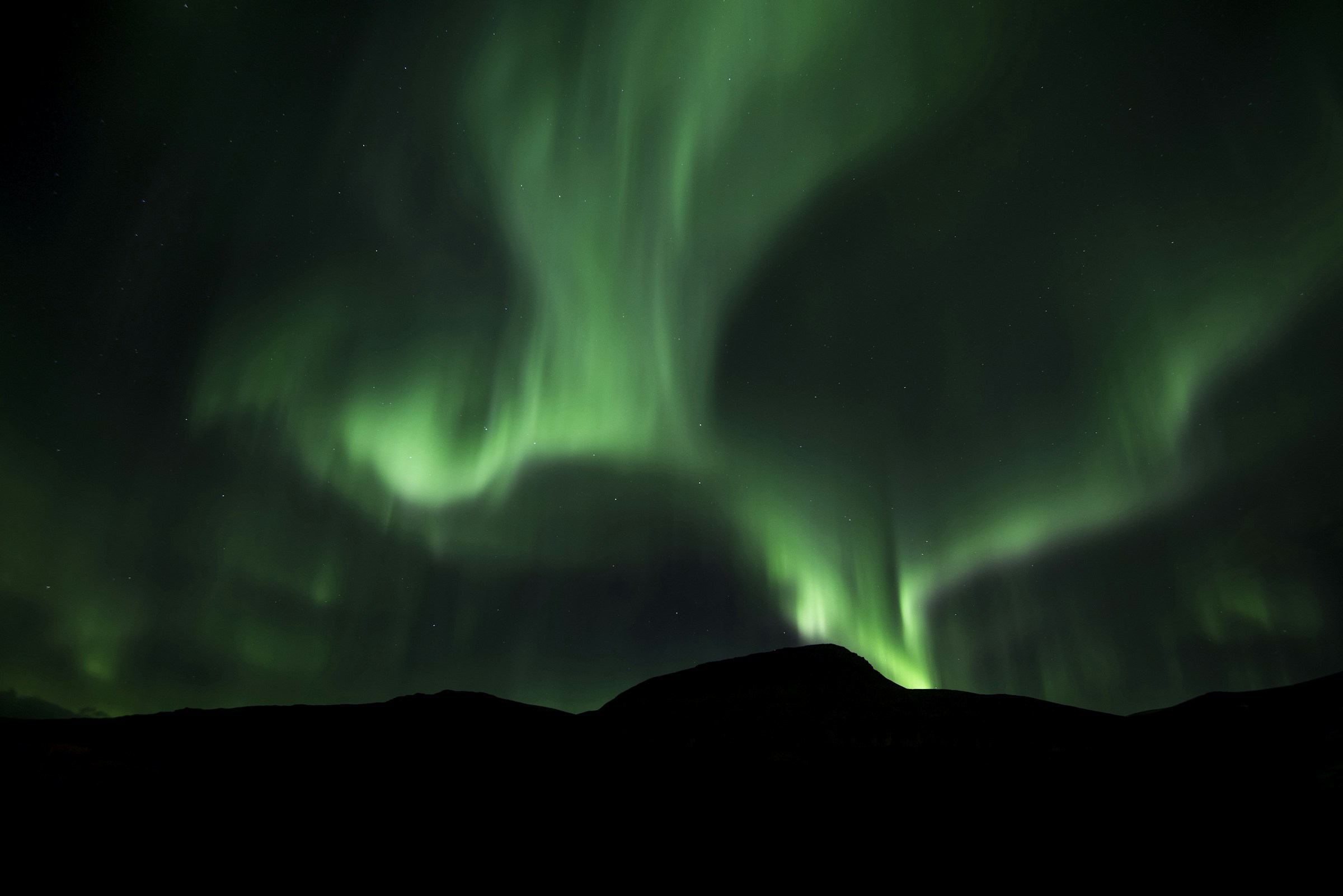Green aurora borealis lighting up the night sky with stars visible over Iceland
