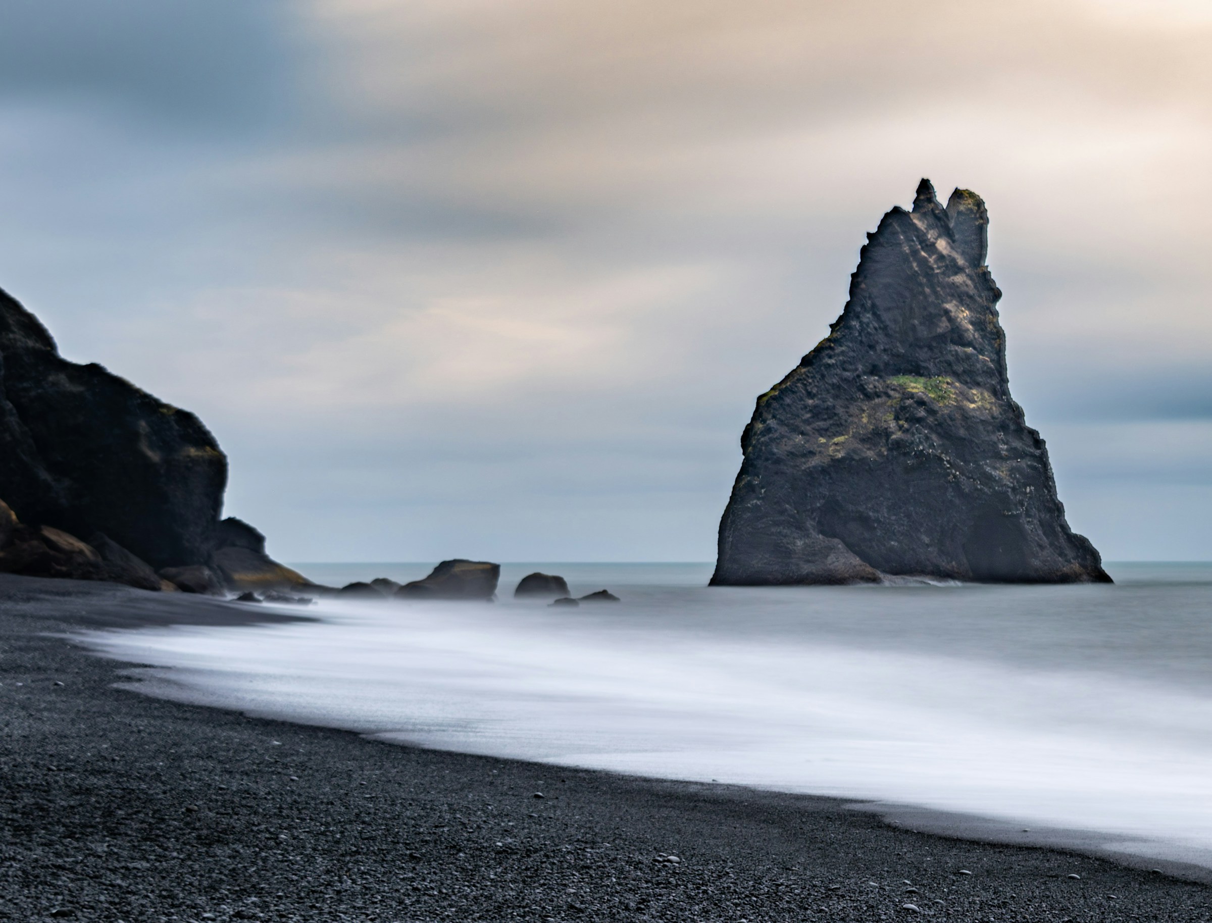 Basalt sea stacks rising from the black sand of Reynisfjara beach, Iceland, under twilight