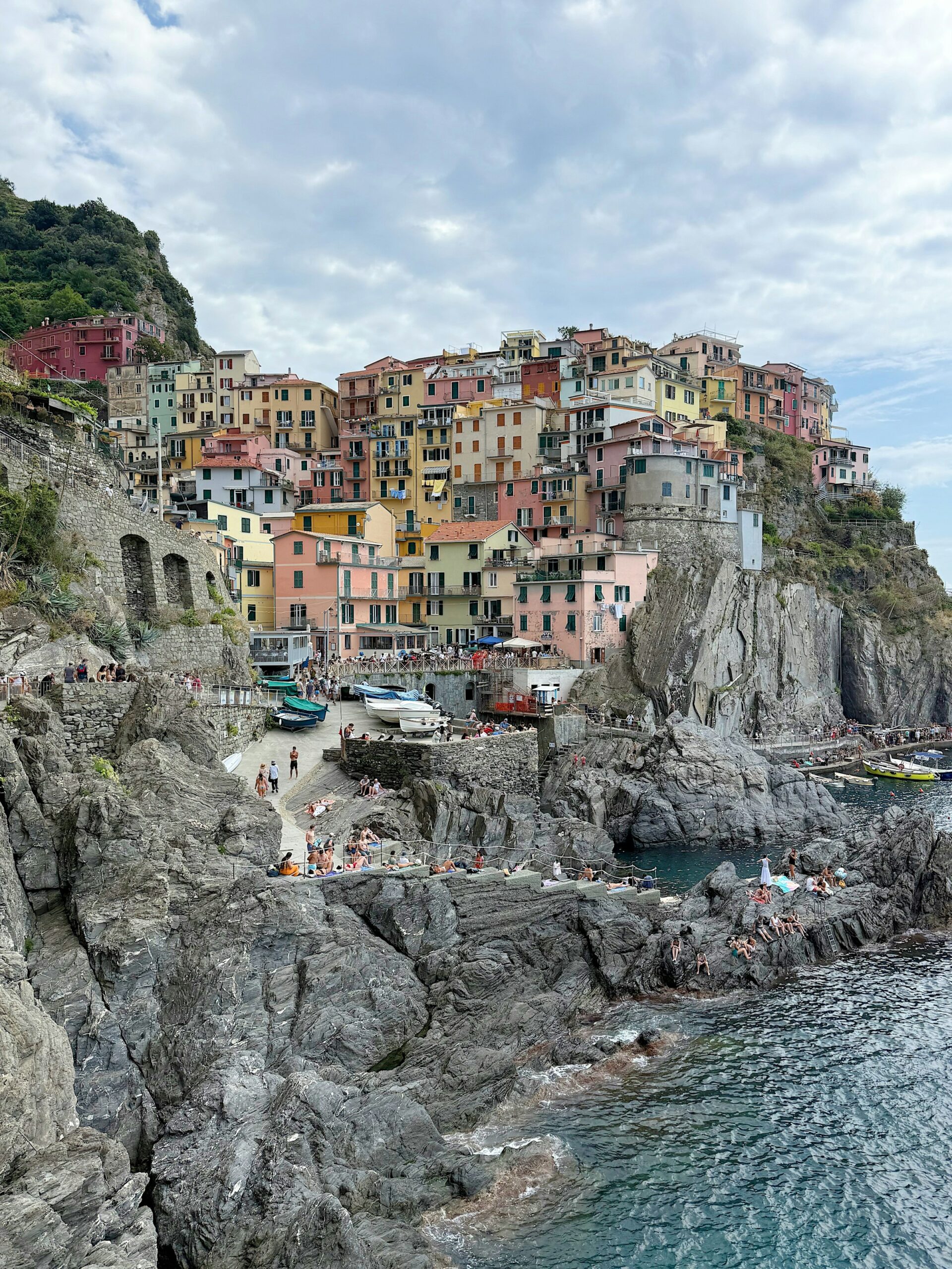 Brightly colored buildings clinging to a rocky cliff above the sea in Cinque Terre, Liguria, Italy