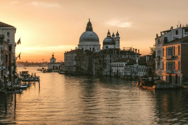 A Venetian canal lined with historic buildings, glowing in warm sunset light