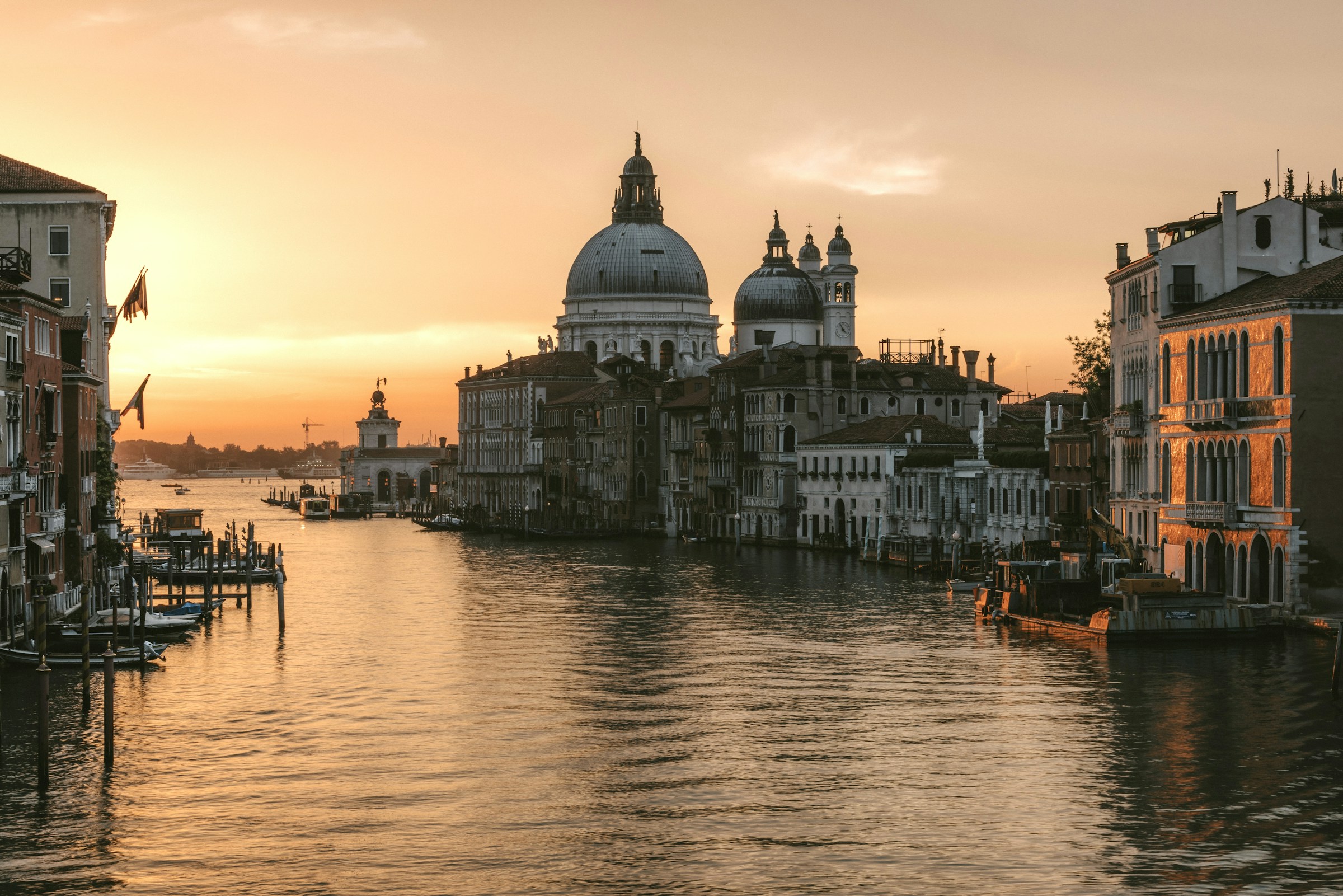A Venetian canal lined with historic buildings, glowing in warm sunset light