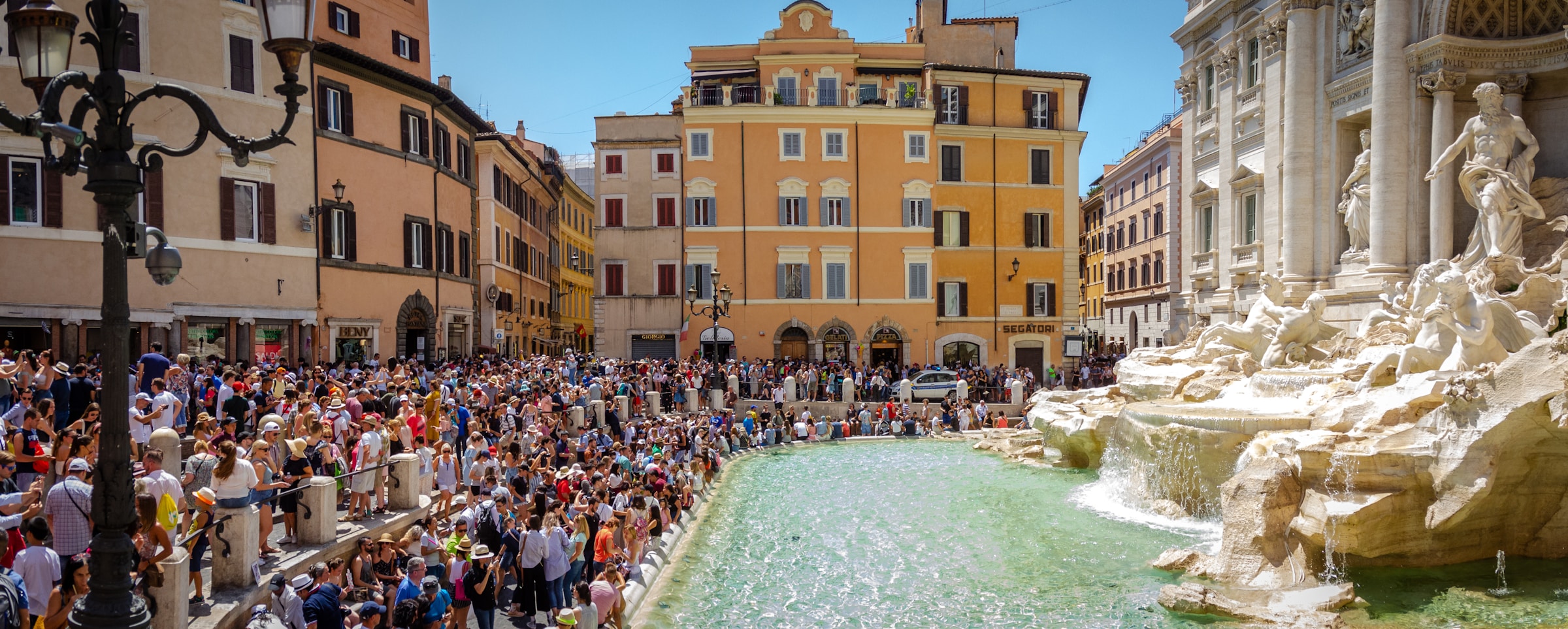 A dense crowd of tourists gathered in front of the Trevi Fountain in Rome, Italy