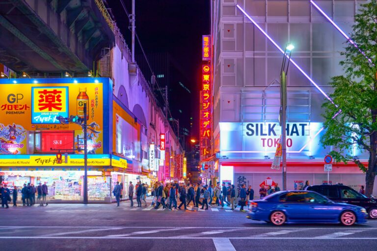 Illuminated neon signs above a busy pedestrian street at night in Akihabara, Tokyo, Japan