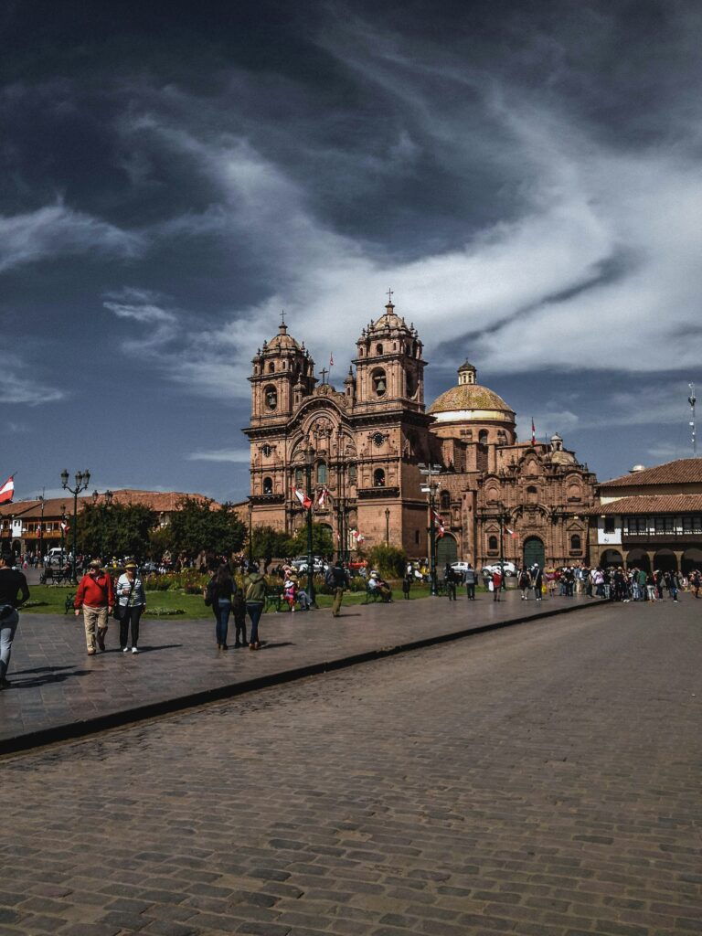 Cusco's colonial cathedral and Plaza de Armas with people walking below the Andes mountains