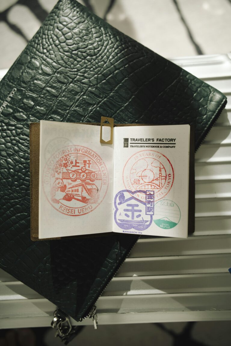An open passport showing colorful entry and exit stamps alongside travel accessories