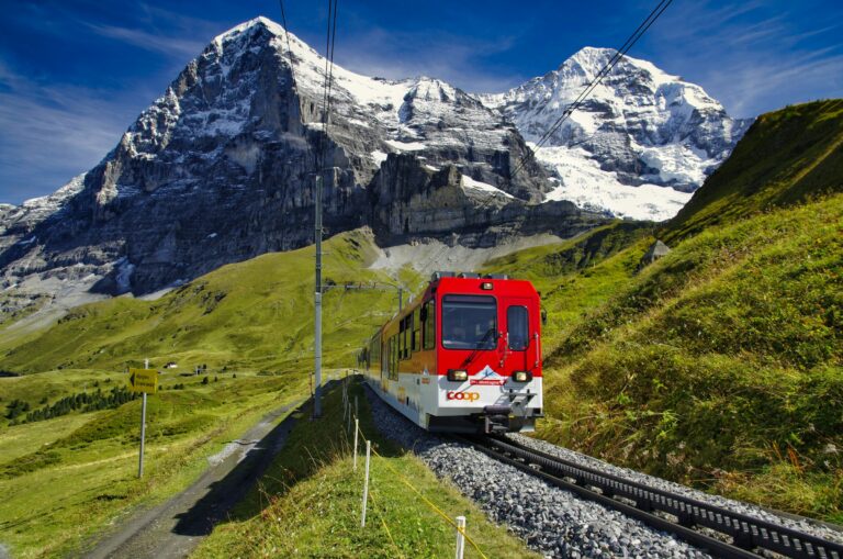 A red and white train on a mountain railway near the snow-covered Eiger peak in the Swiss Alps