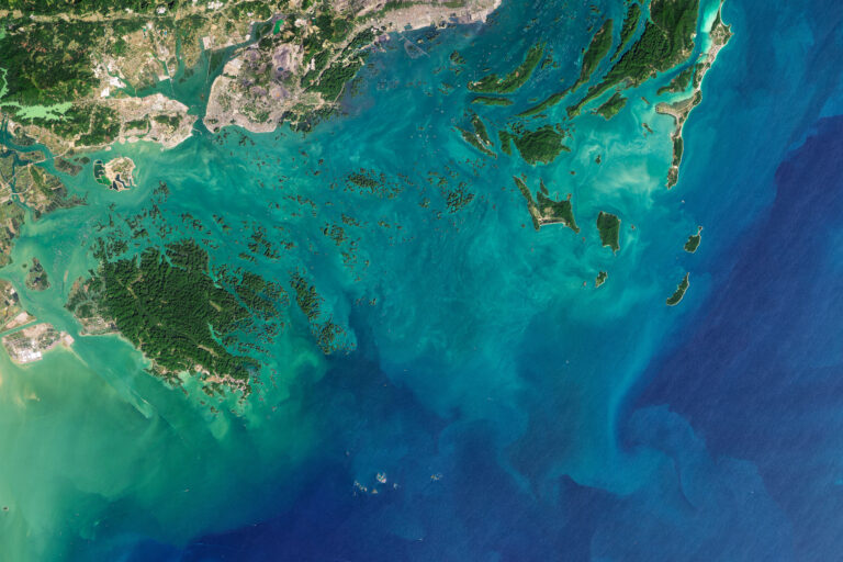 A traditional longtail boat anchored in a turquoise limestone karst lagoon in Thailand