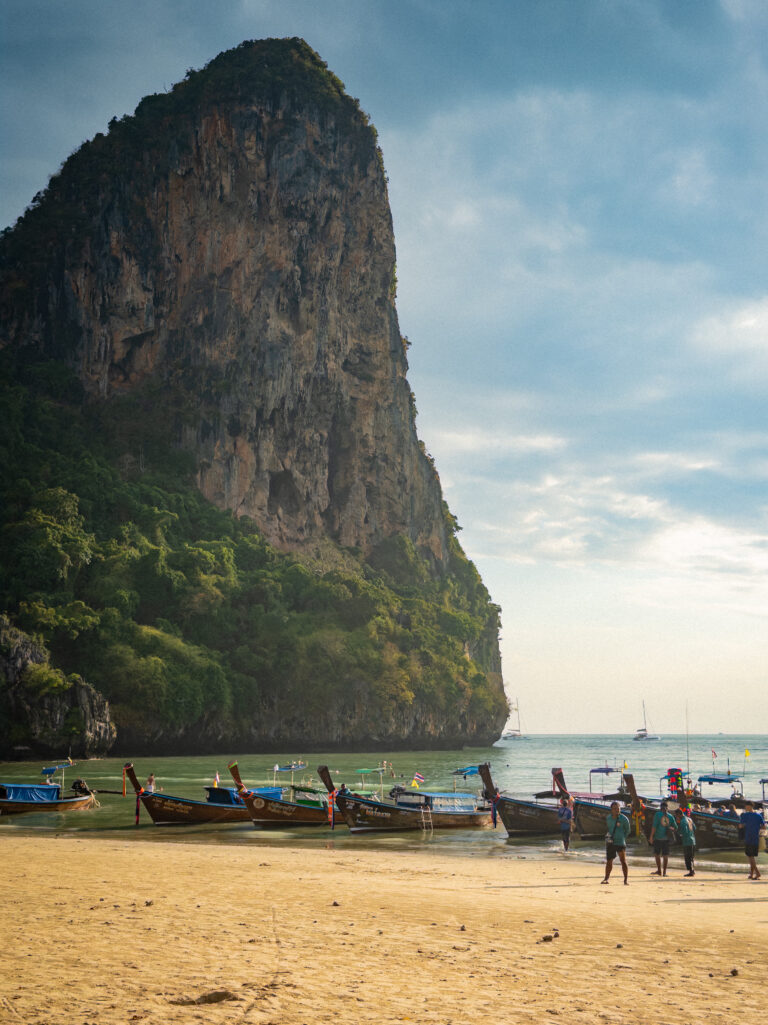 Traditional longtail boats moored at Railay Beach, Thailand, beneath limestone cliffs